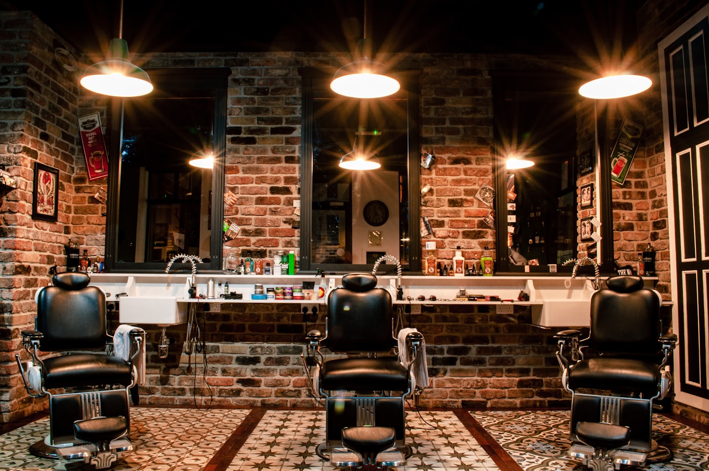 Warmly lit barbershop with premium leather chairs against an exposed brick wall