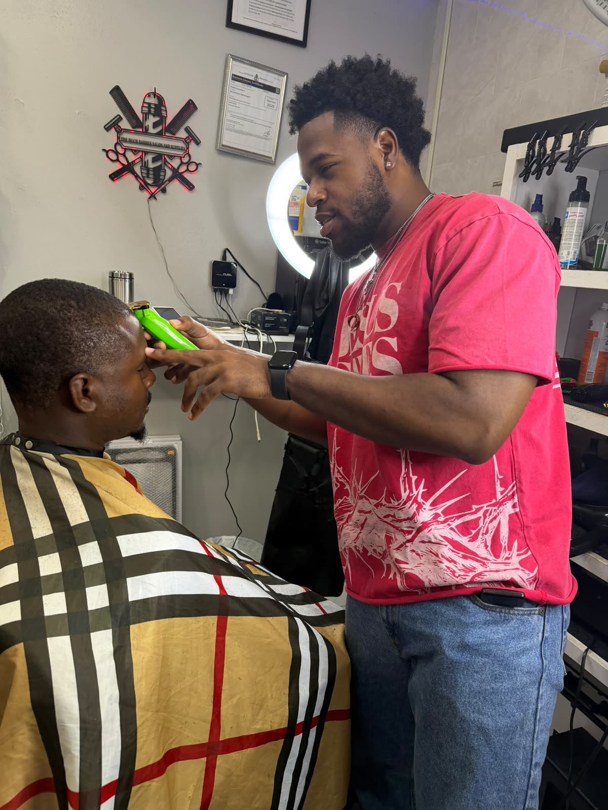 A Duch Barber barber detailing a client's hairline in the shop